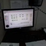 Computer monitor displaying software interface with data and documents on a desk, relevant to IT services and Eric Walper's expertise at Clear Sailing IT Services.